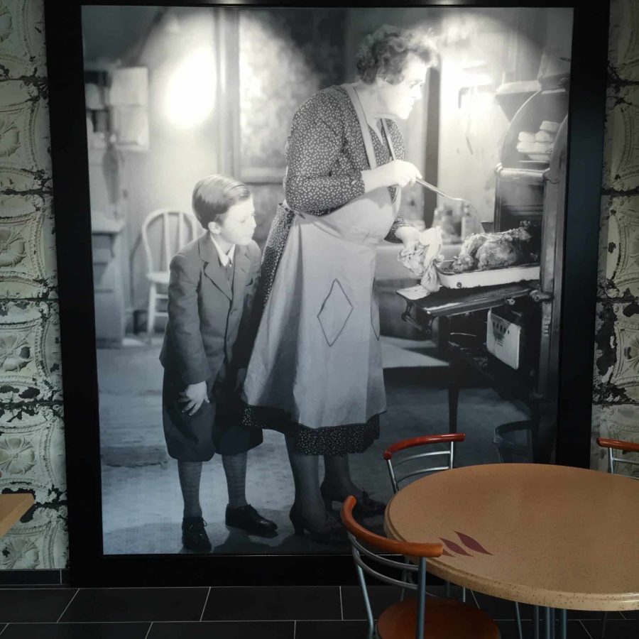 photo d'un mur imprimé en n&b avec une photo d'une femme sortant un poulet du four et de son petit-fils qui la regarde